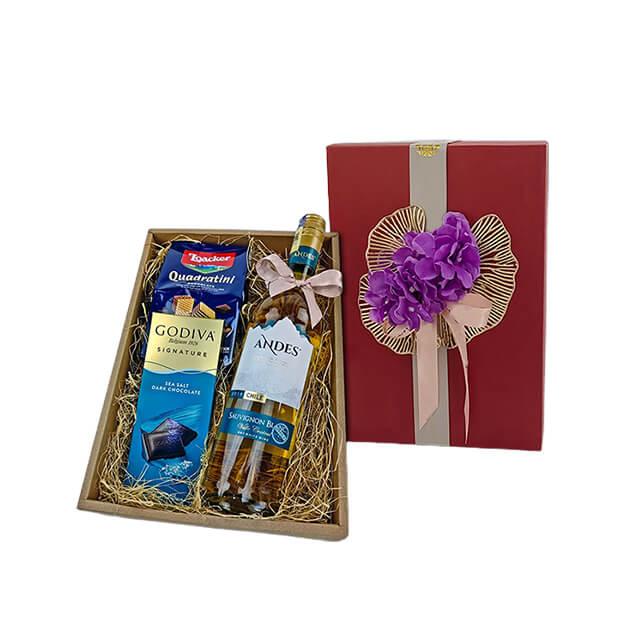 Gift box with a bottle of Andes white wine, Godiva dark chocolate, Loacker Quadratini wafers, decorated with purple flowers and ribbon