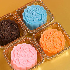 Colorful floral-patterned mooncakes in gold plastic trays on golden surface
