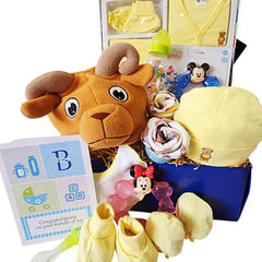 Baby gift hamper with plush ram toy, yellow baby clothes, bottle, mittens, teething toys, and a congratulations card