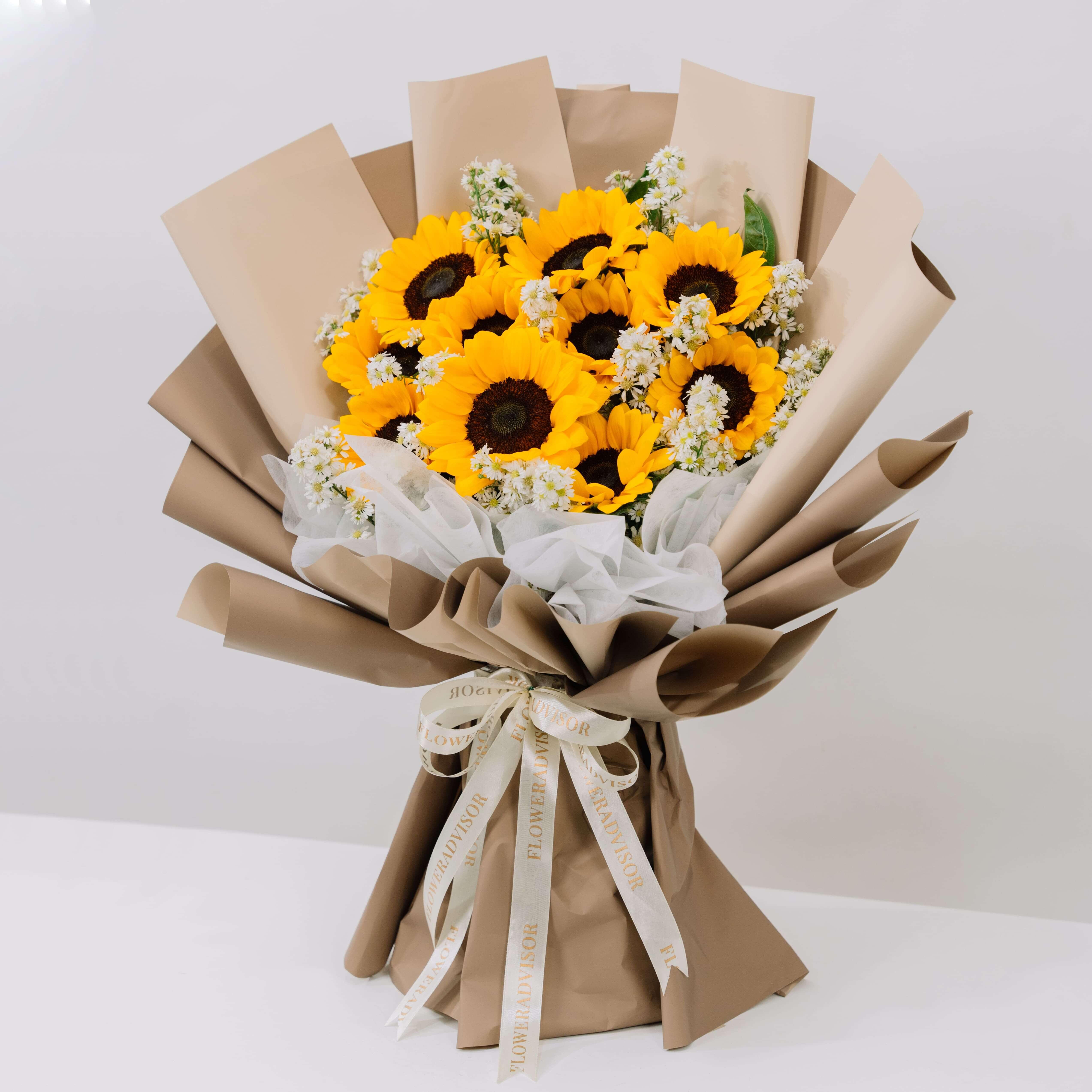 Sunflower bouquet with white filler flowers wrapped in brown paper and tied with FlowerAdvisor ribbon