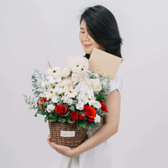 Woman holding basket with red roses, white flowers, teddy bear, and gift card by FlowerAdvisor Malaysia
