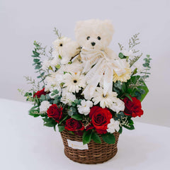 Basket bouquet with red roses, white flowers, greenery, and a white teddy bear with a FlowerAdvisor ribbon