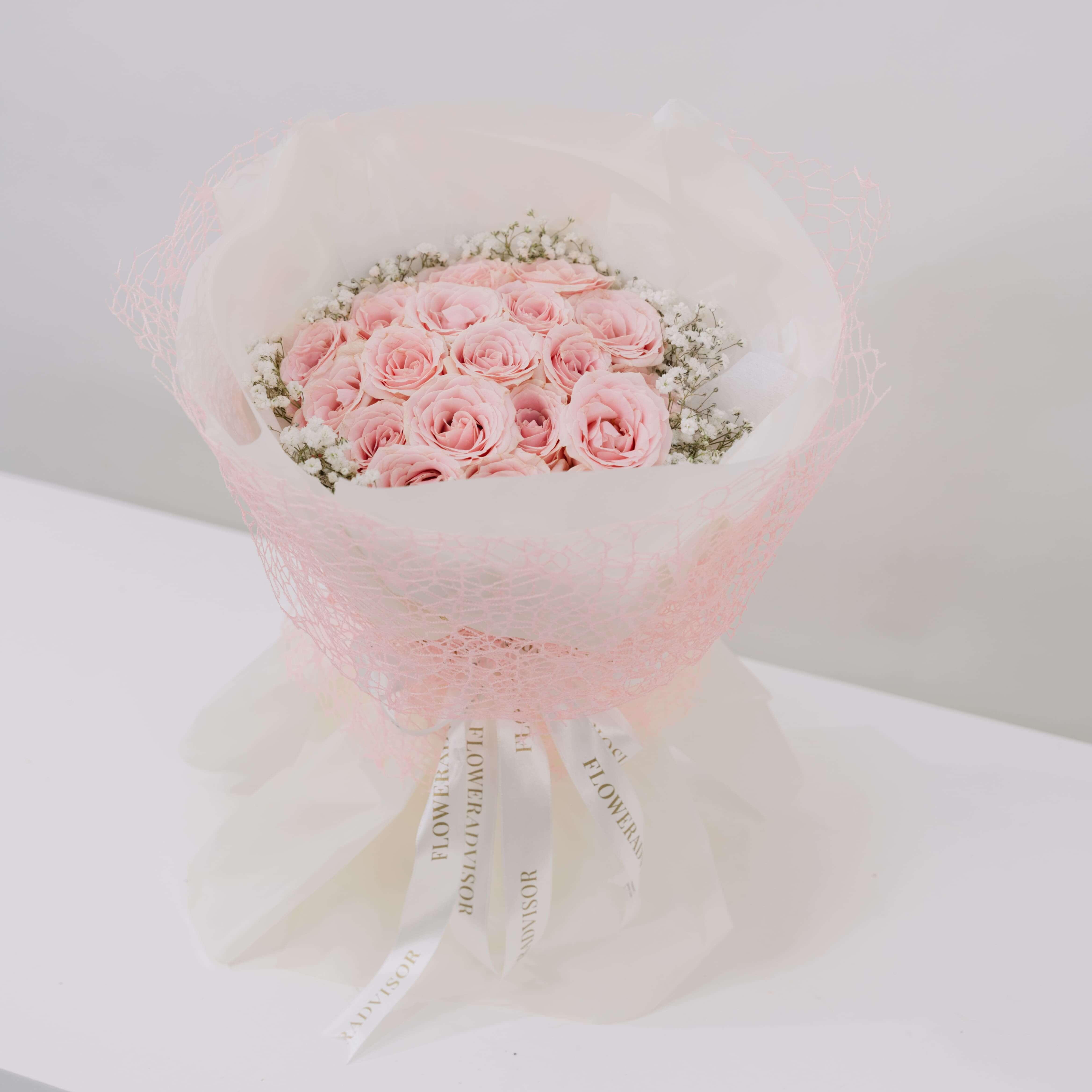 Bouquet of fresh pink roses wrapped in pink mesh and white paper with FlowerAdvisor ribbon