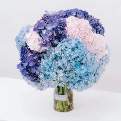 Bouquet of fresh blue, purple, and pink hydrangeas in a clear glass vase by FlowerAdvisor Malaysia