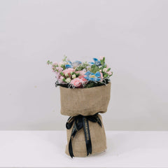 Elegant bouquet with pink and blue flowers wrapped in burlap and tied with black FlowerAdvisor ribbon