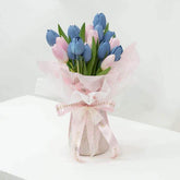 Bouquet of blue and pink tulips wrapped in pink and white paper with lace ribbon, fresh flower delivery