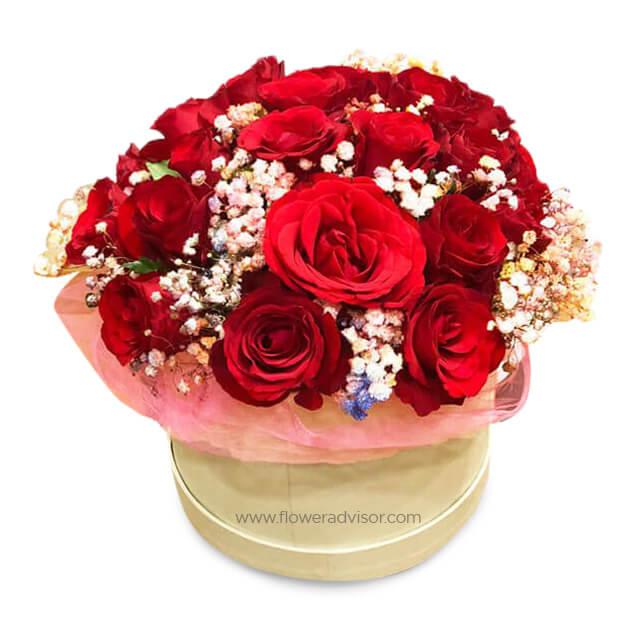 Elegant round bouquet of vibrant red roses and white baby's breath in a beige box, fresh flower delivery