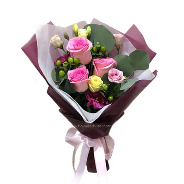 Fresh flower bouquet with pink and yellow roses, green berries, and eucalyptus wrapped in maroon and white paper