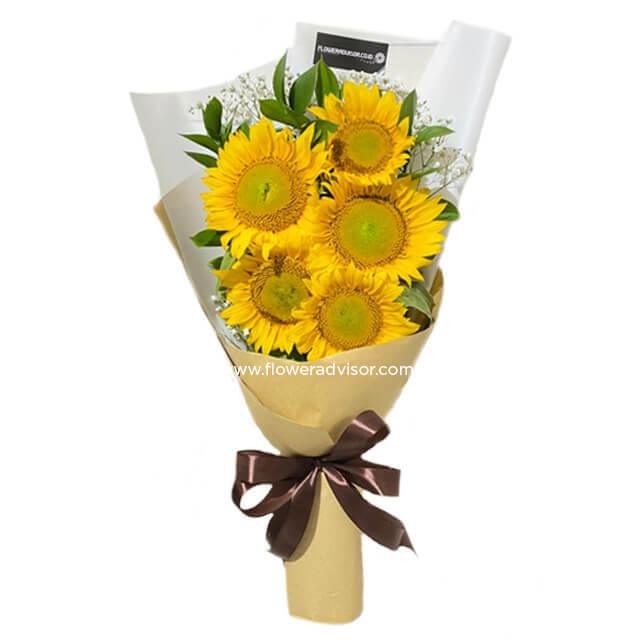 Bright sunflower bouquet wrapped in beige and white paper with brown ribbon, fresh greenery and baby's breath accents