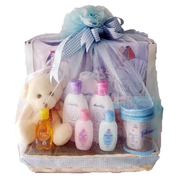 Gift basket with baby care products, teddy bear, and blue decorative ribbon, ideal for newborns