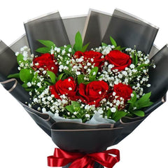 Elegant bouquet of red roses and white baby's breath with greenery wrapped in black paper
