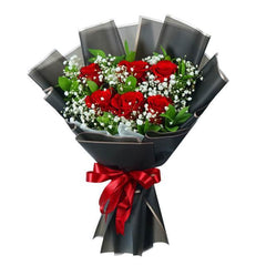 Bouquet of fresh red roses and white baby's breath wrapped in black paper with a red ribbon