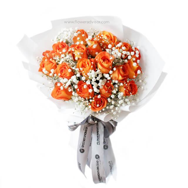 Fresh orange rose bouquet with white baby's breath flowers wrapped in white paper and branded ribbon