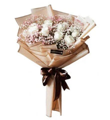 Elegant bouquet of white roses and pink baby's breath wrapped in beige paper with brown ribbon