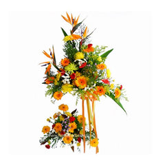 Tall floral arrangement with orange birds of paradise, yellow and orange flowers, and green foliage