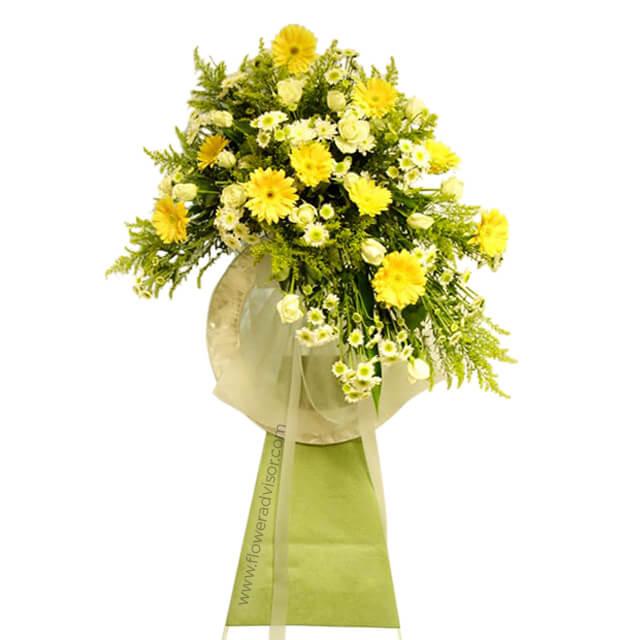 Elegant yellow and white flower bouquet with daisies and greenery on green stand