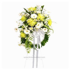 Yellow and white floral sympathy wreath with green leaves and white ribbons on white background