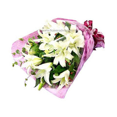 Elegant bouquet of fresh white lilies wrapped in pink floral paper with green foliage, ideal for flower delivery