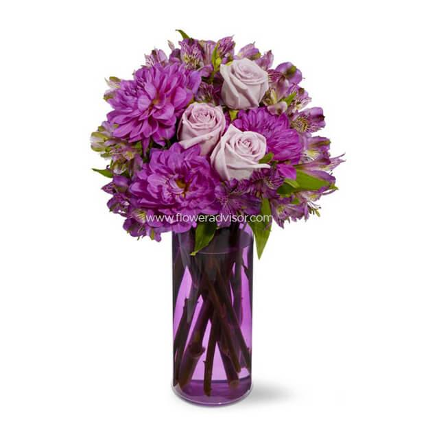 Purple and lavender flower bouquet with roses and dahlias in a purple glass vase on white