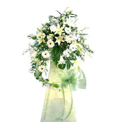 Elegant white and cream flower arrangement with lilies and daisies in a green vase with ribbon