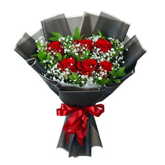 Bouquet of fresh red roses with baby's breath, green leaves, wrapped in black paper and a red ribbon