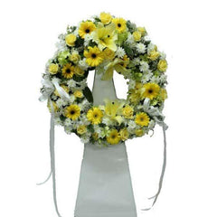Yellow and white funeral flower wreath with lilies, roses, and chrysanthemums on stand