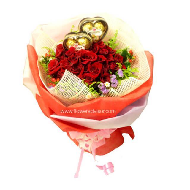 Hand bouquet of fresh red roses and gold chocolate hearts wrapped in decorative paper