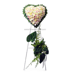 Heart-shaped pastel rose floral arrangement on a stand with green leaves