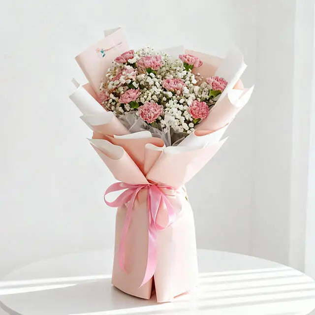 Pink carnation and baby's breath hand bouquet in pastel wrapping