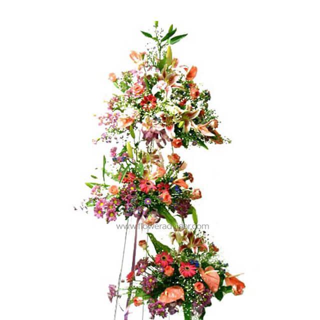 Stand arrangement with pink carnations, daisies, and lilies, lush greenery accents