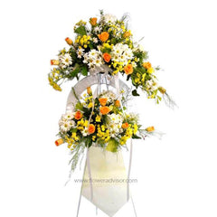 Standing flower arrangement with orange roses, white daisies, and yellow blooms on a stand