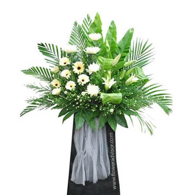 White gerbera daisies and white lilies in a large standing bouquet with lush green leaves