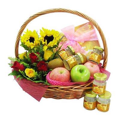 FlowerAdvisor gift basket with sunflowers, red and yellow roses, apples, honey jars, and pink ribbon