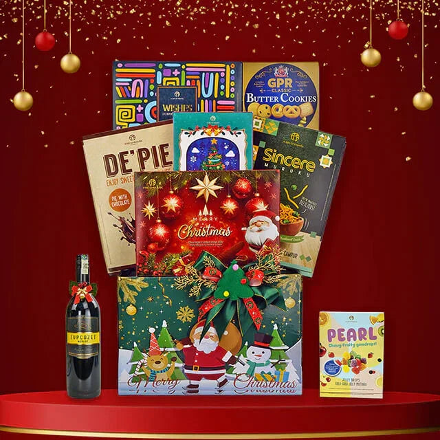 Christmas gift hamper with festive Santa and snowman box, assorted cookies, chocolates, and wine bottle on red background