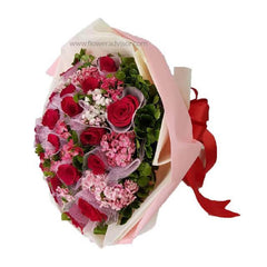 Bouquet of 12 red roses with pink sweet william flowers and greenery, wrapped in pink paper