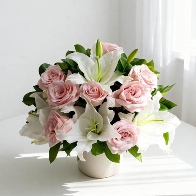 Elegant pink roses and white lilies floral arrangement in a white vase on a table