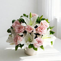 Elegant pink roses and white lilies floral arrangement in a white vase on a table