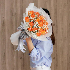 Woman holding a bouquet of orange roses and white baby's breath flowers