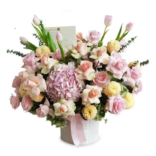 Vase of mixed flowers with pink roses, hydrangeas, tulips, and chrysanthemums
