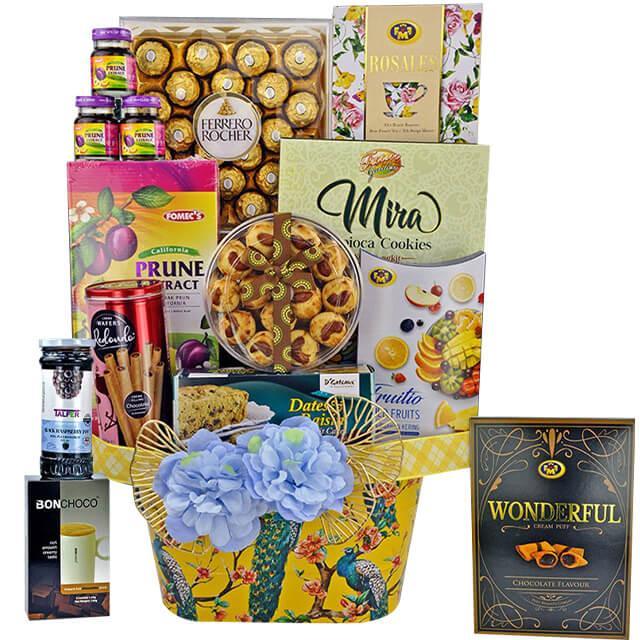 FlowerAdvisor Malaysia gift hamper with Ferrero Rocher chocolates, prune extract, cookies, fruit candy, and decorative blue flowers