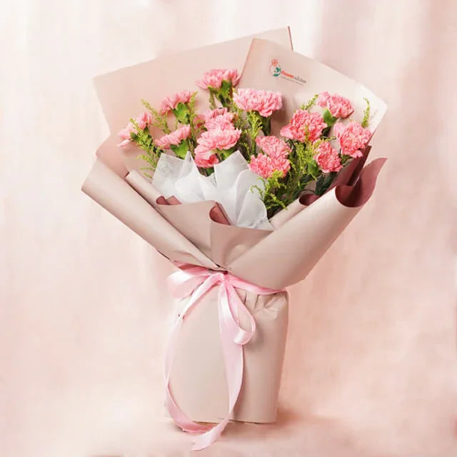 Pink carnation bouquet wrapped in beige paper with pink ribbon, fresh flower delivery by FlowerAdvisor Malaysia