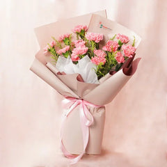 Pink carnation bouquet wrapped in beige paper with pink ribbon, fresh flower delivery by FlowerAdvisor Malaysia