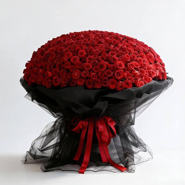 Large bouquet of fresh red roses wrapped in black tulle with a red ribbon bow
