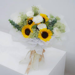Elegant bouquet of sunflowers, white roses, and greenery wrapped in white paper with beige ribbon