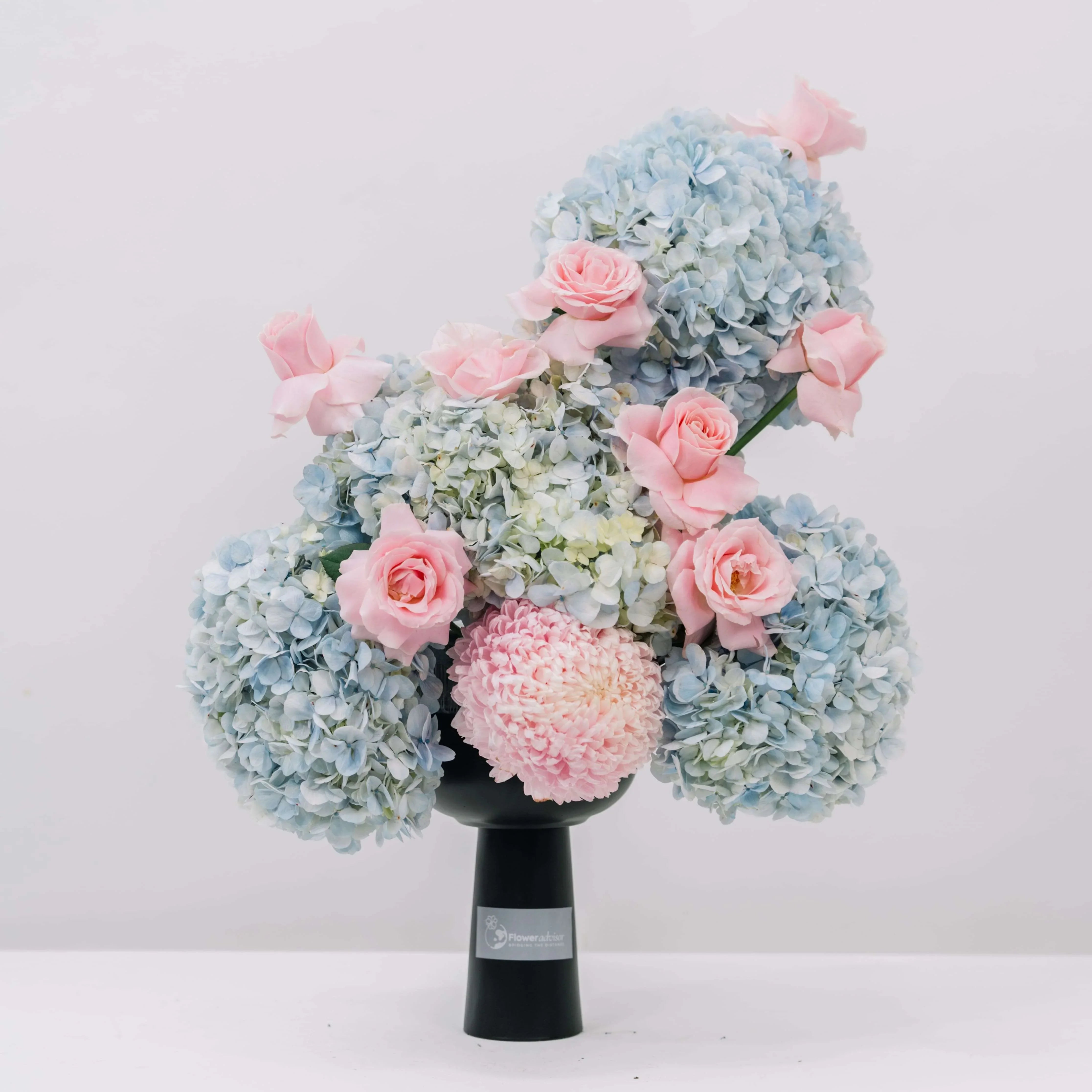 Elegant flower arrangement with blue hydrangeas and soft pink roses in black FlowerAdvisor vase