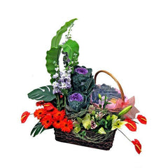 Fruit and flower arrangement in a wicker basket with lilies, gerberas, and greenery