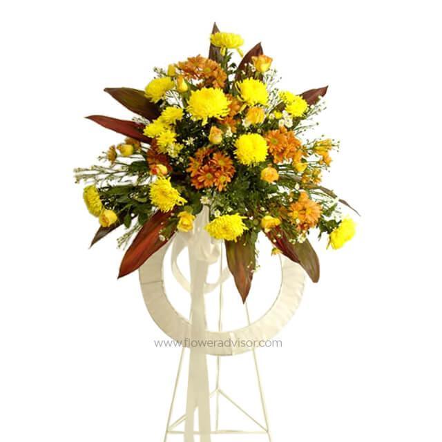 Standing floral arrangement with yellow and orange chrysanthemums on white stand