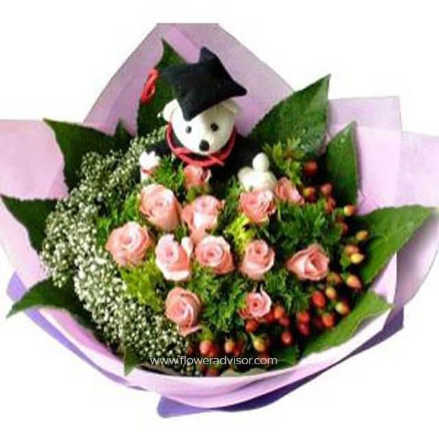 Graduation bouquet with pink roses, greenery, berries, and a plush bear in a cap