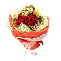 Hand bouquet of fresh red roses and gold chocolate hearts wrapped in decorative paper