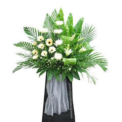 White gerbera daisies and white lilies in a large standing bouquet with lush green leaves